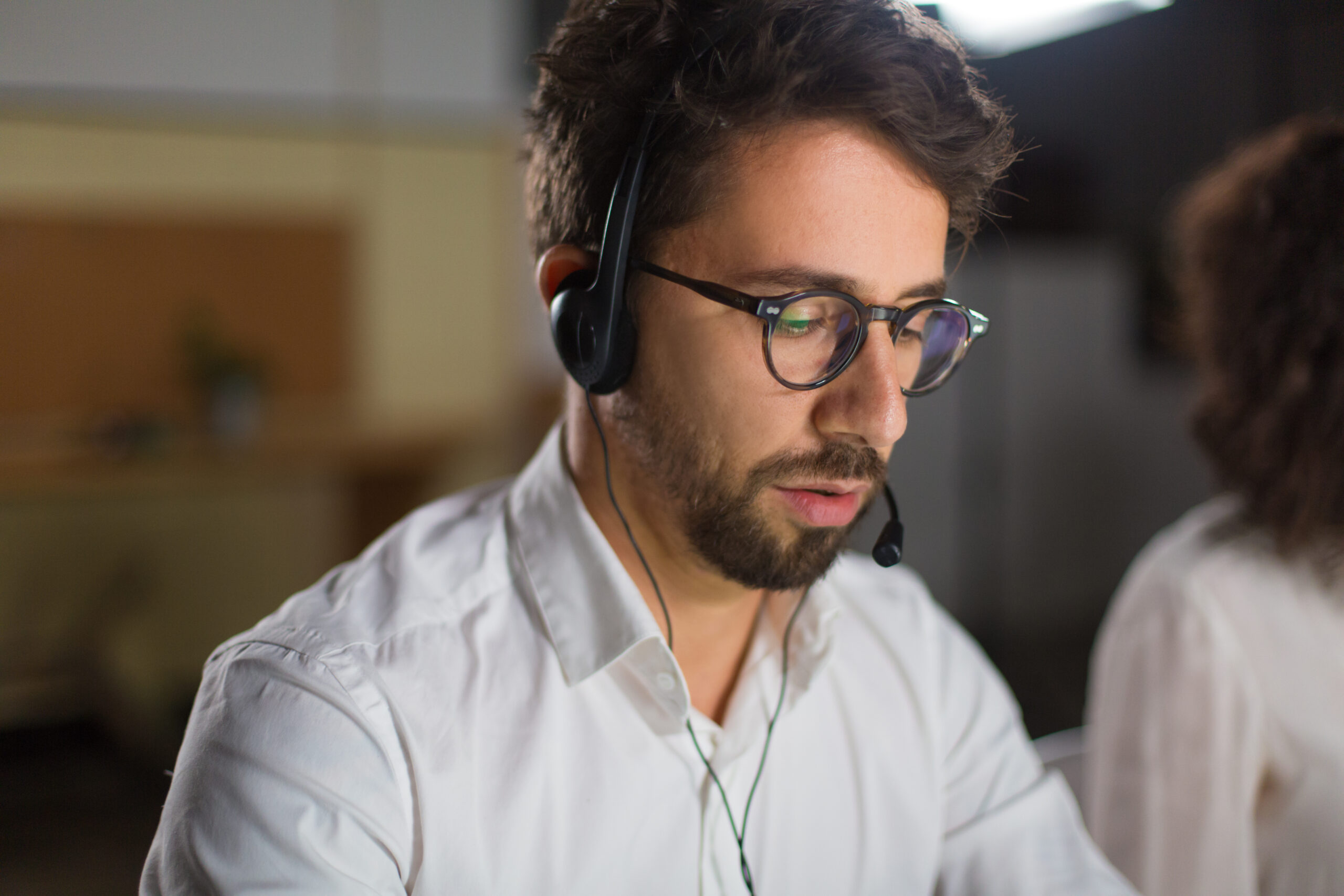 Closeup shot of confident call center operator. Handsome young man with headset looking down. Call center concept
